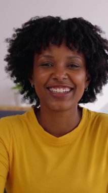 Dizüstü bilgisayar araması sırasında oturma odasında kameraya konuşan neşeli, genç Afrikalı Amerikalı bir kadın. Gülümseyen kadın arkadaşlarıyla ya da meslektaşlarıyla sanal online görüşme yoluyla sohbet ediyor..