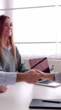 Mutlu gülümseyen milenyum çifti anlaşma ya da kontrat imzaladıktan sonra ofiste üst düzey kadın emlakçılarla tokalaşırken gösteren dikey HD videosu..