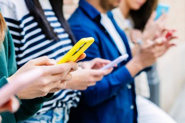 Bir grup arkadaş dışarıda akıllı telefon kullanıyor, sosyal medyada içeriği paylaşıyor ve mobil teknolojinin tadını çıkarıyor. Gençlik ve teknoloji yaşam tarzı konsepti