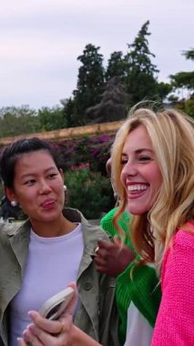 Dışarıda birlikte gülen mutlu genç bir kadın grubunun dikey HD videosu. Farklı kültürlerden yedi kızla olan kadın arkadaşlığı kavramı şehir sokaklarında kaynaşıyor. Yavaş çekim görüntüleri.