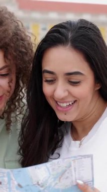 Dikey video. Lizbon, Portekiz, Avrupa 'da tatilin tadını çıkarırken şehir haritasında yön arayan mutlu genç kızlar. Tatil yaşam tarzı ve arkadaşlık kavramı.