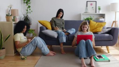 Üç genç kız öğrenci oturma odasında birlikte ders çalışıyor. Millennial bir grup kadın öğrenci aynı apartmanda üniversite atamaları üzerinde çalışıyor. Eğitim yaşam tarzı konsepti.