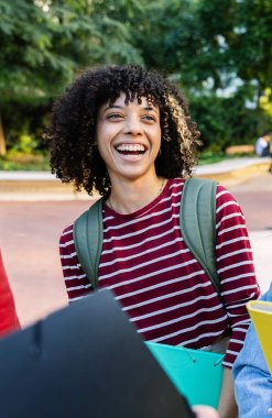 Kampüsteki arkadaşlarıyla konuşan Afrikalı Amerikalı genç bir kızın dikey çekimi. Üniversite derslerinden sonra milenyum sınıf arkadaşları dinleniyor. Üniversite yaşam tarzı ve eğitim kavramı.