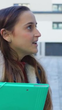 Üniversite kampüsünde arkadaşlarıyla takılan genç üniversite öğrencisinin dikey HD videosu. Eğitim ve gençlik yaşam tarzı kavramı.