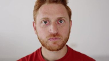 Neşeli genç adam komik suratlar yapıyor. Oyuncu kızıl saçlı adam izole edilmiş arka planda kameraya bakıyor.