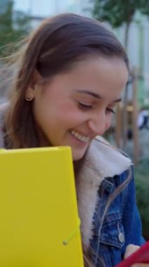 Dersten sonra üniversite kampüsünden çıkarken cep telefonu kullanan beyaz bir kızın dikey HD videosu. Eğitim ve teknoloji kavramı.