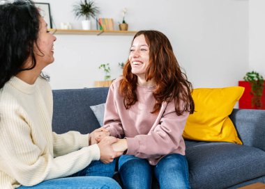 İki genç mutlu kadın evdeki kanepede birlikte vakit geçiriyorlar..