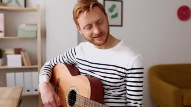 Evde bilgisayarlı uzaktan öğretmenle çevrimiçi müzik dersinde gitar öğrenen genç yetişkin bir adam dizüstü bilgisayarla müzik öğretiyor. Uzaklık eğitimi öğrenme kavramı