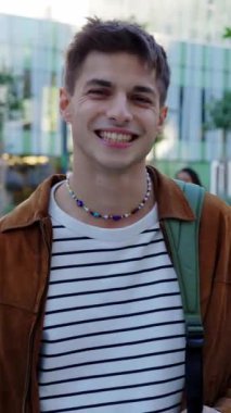 Üniversite kampüsünde kameraya bakan genç İtalyan öğrencinin dikey portresi. Eğitim kavramı