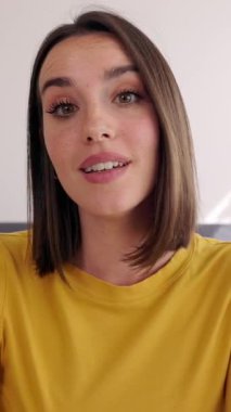 Dikey video. POV 'un mutlu genç bayanı laptoptaki video görüntülerini dinliyor ve evden çalışıyor. Genç girişimci bayan partnerle çevrimiçi görüşme yoluyla konuşuyor. İş adamları konsepti