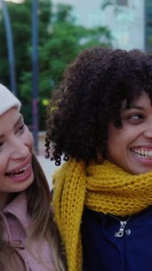 Üç mutlu genç kızın birbirine sarılıp sıcak giysiler içinde birbirlerine sarılırken çekilmiş dikey HD videosu. Gençlik ve kadın arkadaşlık kavramı