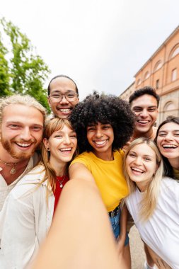 Genç milenyum insanlarının şehir caddesinde akıllı cep telefonuyla selfie çektikleri dikey bir fotoğraf. Gençlik toplumu ve arkadaşlık kavramı.