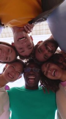 Dikey HD video. Genç üniversite öğrencisi arkadaşlar toplanıp kameraya bakıyorlar. Farklı milenyum insanlarının birlikte eğlendikleri gülümseyen portresi. Gençlik toplumu konsepti. Alt görünüm