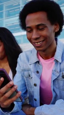 Dışarıda cep telefonu kullanan çok ırklı genç arkadaşların dikey HD videosu. Çeşitli Gen Z öğrencileri cep telefonu uygulamasından sosyal medya içeriğini izliyor. Teknoloji ve gençlik yaşam tarzı kavramı