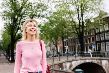 Amsterdam 'da yürüyen mutlu genç bayan turist. Güzel bir milenyum kadını yaz tatilinde Hollanda 'yı geziyor. Seyahat yaşam tarzı konsepti.
