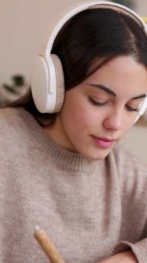 Kulaklık takan ve online öğrenim için laptop kullanan mutlu genç öğrencinin dikey HD videosu. Eğitim ve e-öğrenim kavramı