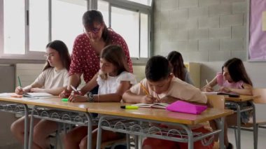 İlkokuldaki sınıfta ilkokul öğrencisine asistanlık yapan genç bayan öğretmen. Eğitim kavramı.