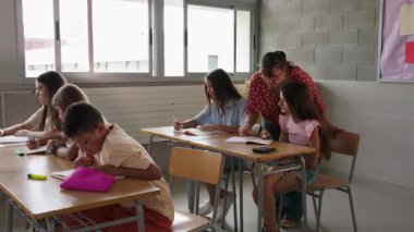 İlkokulda sınıf dersinde ilkokul öğrencisine asistanlık yapan bayan öğretmen. Eğitim kavramı.