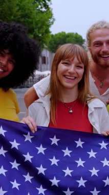Amerika Birleşik Devletleri bayrağını açık havada tutarken kameraya gülümseyen çeşitli Amerikalı gençlerin dikey HD videosu. Farklı milletlerden gelen uluslararası toplum birlik gösteriyor.