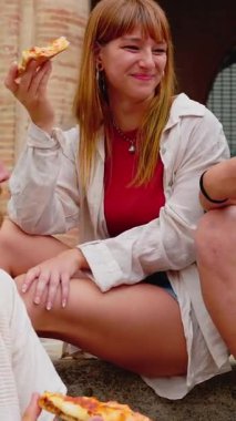 İtalya 'da yaz tatilinin tadını çıkarırken arkadaşlarıyla pizza yiyen genç kadının dikey HD videosu. Arkadaşlık ve gençlik yaşam tarzı konsepti