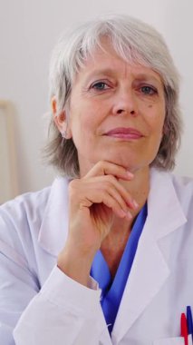 Dikey video. Hastanedeki tıp odasındaki dizüstü bilgisayarlı hastaları dinleyen profesyonel kıdemli kadın sağlık görevlisi. Sanal toplantı sırasında olgun doktorların POV 'u