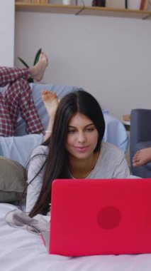 Evde arkadaşlarıyla pijama partisi yaptıktan sonra dizüstü bilgisayar kullanan genç bir kızın dikey HD videosu.