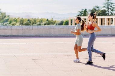Yazın dışarıda koşan mutlu genç kadınlar. İki bayan koşucu dışarıda antrenman yapıyor. Sağlıklı yaşam tarzı kavramı.