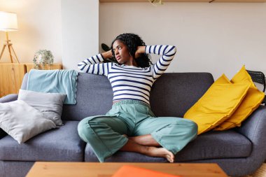 Genç siyahi kadın rahat koltukta dinleniyor ve evde tatilin tadını çıkarıyor. Ev hayatı kavramı