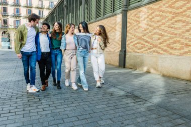 Şehir caddesinde birlikte gülen bir grup arkadaş. Birleşmiş Milenyum insanları tatilde eğlenirken birbirlerine sarılıyorlar.