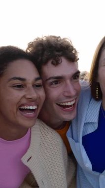 Dışarıda gülüşen mutlu gençlerin birbirine sarıldığı dikey HD videolar. Dost canlısı milenyum dostları şehir caddesinde yan yana durarak eğleniyor. Gençlik toplumu kavramı.