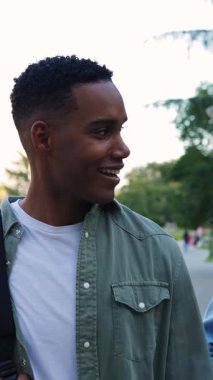 Genç mutlu Afrikalı Amerikalı öğrencinin dersten sonra okuldan çıkışının dikey HD videosu.