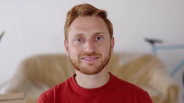 Yeni dairede otururken kameraya bakan mutlu kızıl adamın portresini yakın çekim. Mutlu insanlar, yeni hayat ve başlangıç konsepti