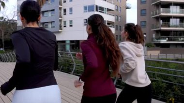 Bayan sporcuların arkadaşları birlikte koşuyor, birlikte şehir parkında koşarken gülümseyen enerjiyi paylaşıyorlar, fitness arkadaşlığını ve sağlık yaşam tarzını temsil ediyorlar.