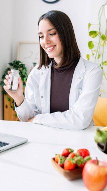 Kadın doktorun hastaya tıbbi tedaviyi video konferans yoluyla açıklarken dikey bir fotoğrafı. Teletıp ve teletıp kavramı.