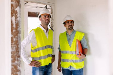 İnşaat alanında ilerleme kaydeden iki mühendis işyeri güvenliği ve işbirliği gösteriyor. Mühendislik ve mimari kavramı