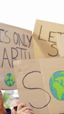 İklim değişikliği için pankart ve pankart tutan aktivist bir grubun dikey HD videosu. Çevre ve gezegen konseptini kurtarmak.