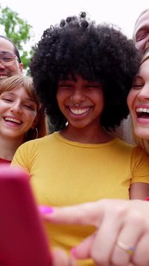 Dışarıda akıllı telefon kullanan bir grup öğrencinin dikey HD videosu. Bağımlı milenyum arkadaş grubu şehir sokaklarındaki cep telefonu uygulamasından sosyal medya içeriğini izlerken eğleniyor.