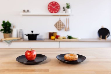 İki tabaklı ahşap masa, biri elmalı, diğeri de donutlu.
