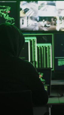 İki hackerın çoklu bilgisayar monitörleri ve güvenlik kamerası görüntüleriyle sunucu güvenliğini kırdığı dikey HD video.