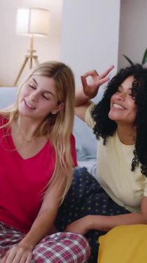 Pijamalı üç mutlu genç kızın, pijama partisinden sonraki gün oturma odasında dinlenirken akıllı telefon kullanarak selfie çekerken çekilmiş dikey HD videosu. Arkadaşlık kavramı