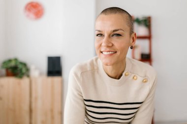 Mutlu orta yaşlı bir kadın iş yerinde oturmuş başka tarafa bakıyor. Girişimci kadın ofiste işe ara veriyor..