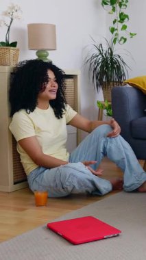 Genç mutlu Afrikalı Amerikalı kızın arkadaşlarıyla oturma odasında takıldığı dikey HD video. Çok ırklı kızlar gülüyor, evde vakit geçiriyorlar. Arkadaşlık ve gençlik kavramı.