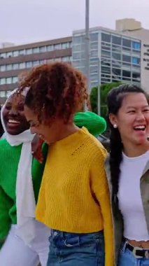 Açık havada eğlenen çoklu etnik gruptaki güzel kadınların dikey HD videosu. Şehir caddesinde yürürken çeşitli bayan arkadaşlar birbirlerine sarılıyorlar. Kadın toplumu kavramı. 