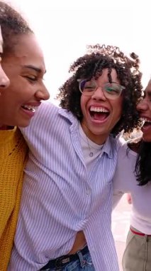 Dışarıda takılan çok ırklı genç kadınların dikey HD videosu. Milenyum bayan arkadaşları birbirlerini kucaklayarak eğleniyorlar. Şehir sokaklarında kaynaşıyorlar..