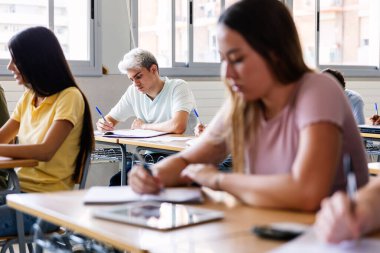 Üniversite sınıfındaki öğretmeni dinlerken not alan bir grup farklı genç öğrenci. Gençler lisede okuyor. Eğitim yaşam tarzı kavramı.