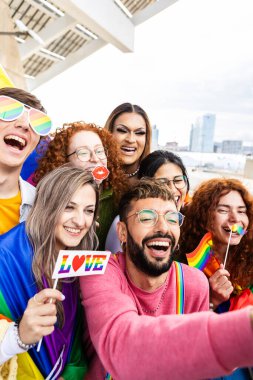 Gökkuşağı bayraklı bir grup genç arkadaş eşcinseller günü festivalini kutluyorlar. LGBT topluluk kavramı.