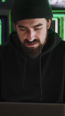Ana ofisinden kurumsal sunuculara sızmaya odaklanan bilgisayar korsanının dikey HD videosu, yeşil kod gösteren birden fazla bilgisayar ekranı ile çevrili.