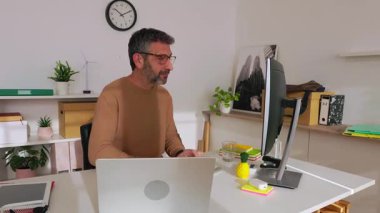 Modern ofiste dizüstü bilgisayarda çalışan kendinden emin bir iş adamı profesyonel bir ortamda odaklanmayı ve üretkenliği gösteriyor. İş ve insan kavramı