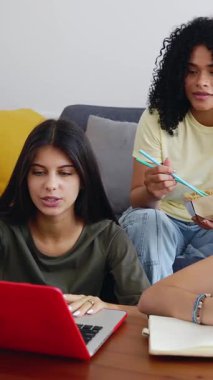 Evde birlikte öğrenen bir grup genç kızın dikey HD videosu. Dizüstü bilgisayarda çalışan üç farklı öğrenci üniversite projesi sunumu hazırlıyor. Takım çalışması ve eğitim kavramı