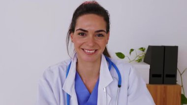 Masada oturan genç bayan doktorun gülümseyen portresi. Kadın çevrimiçi danışmanlık hastalarının bakış açısı. Web kamerası veya laptop ekran görüntüsü 